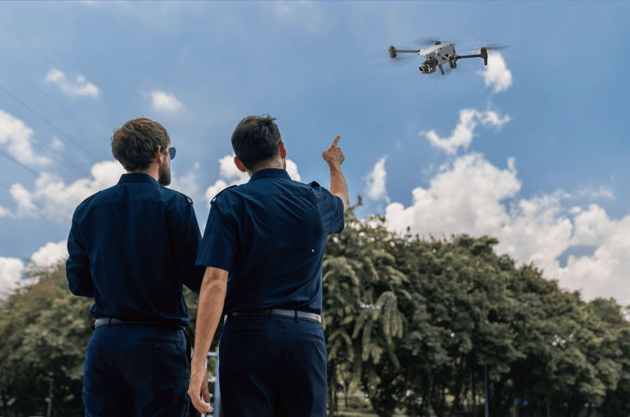 Two men in uniforms observing a Autel Alpha drone in the sky.