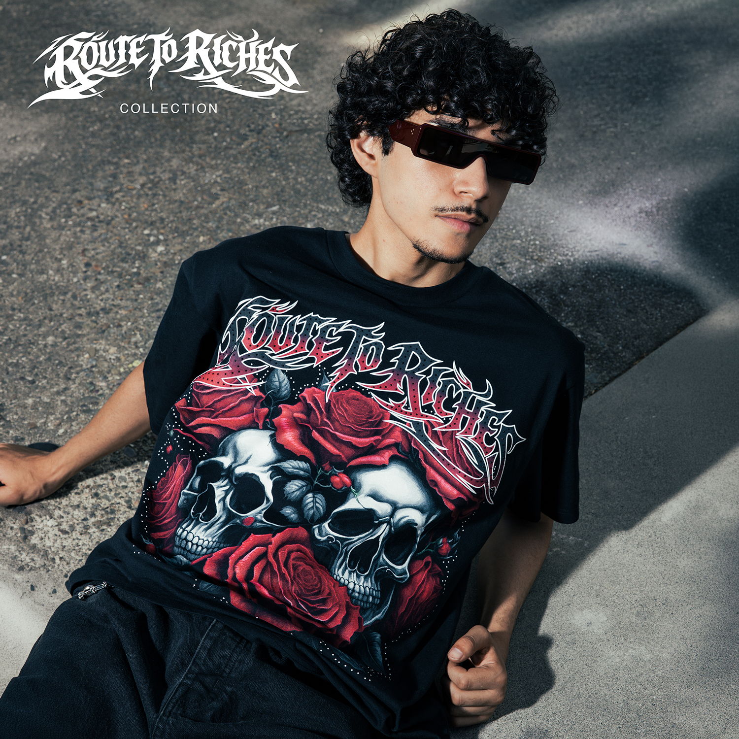 A person wearing a graphic t-shirt with skulls and roses design.