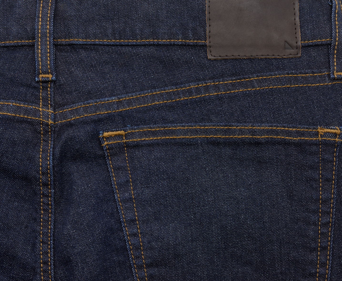 Close-up of the back pocket of dark denim jeans.