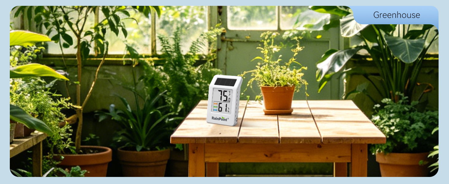 A table with plants and a weather station in a greenhouse.