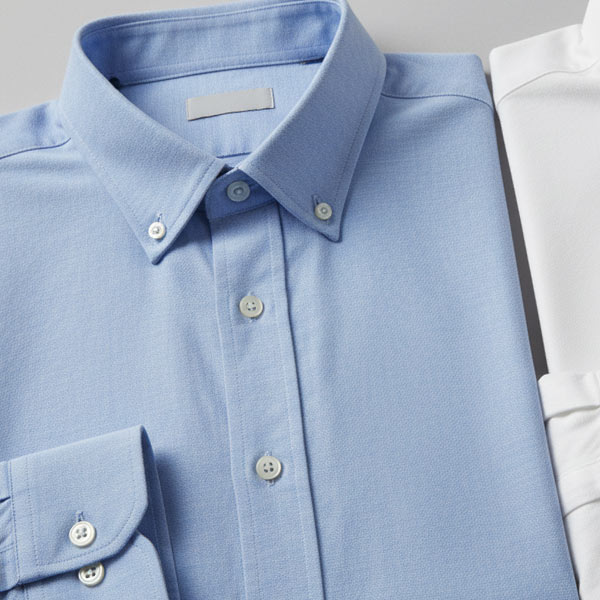 Folded blue oxford dress shirt on a neutral background