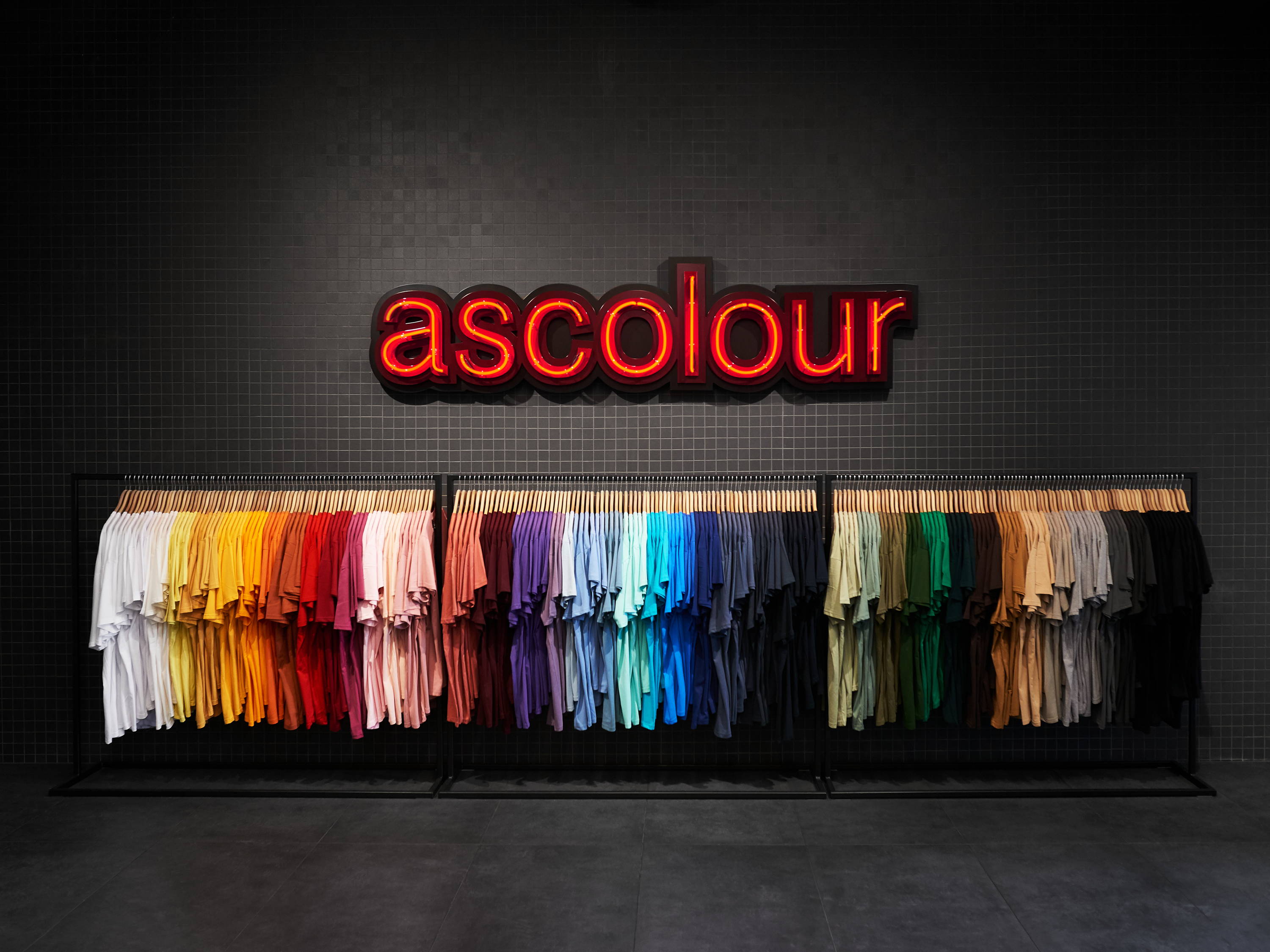 AS Colour sign with range of t-shirts hanging from rack