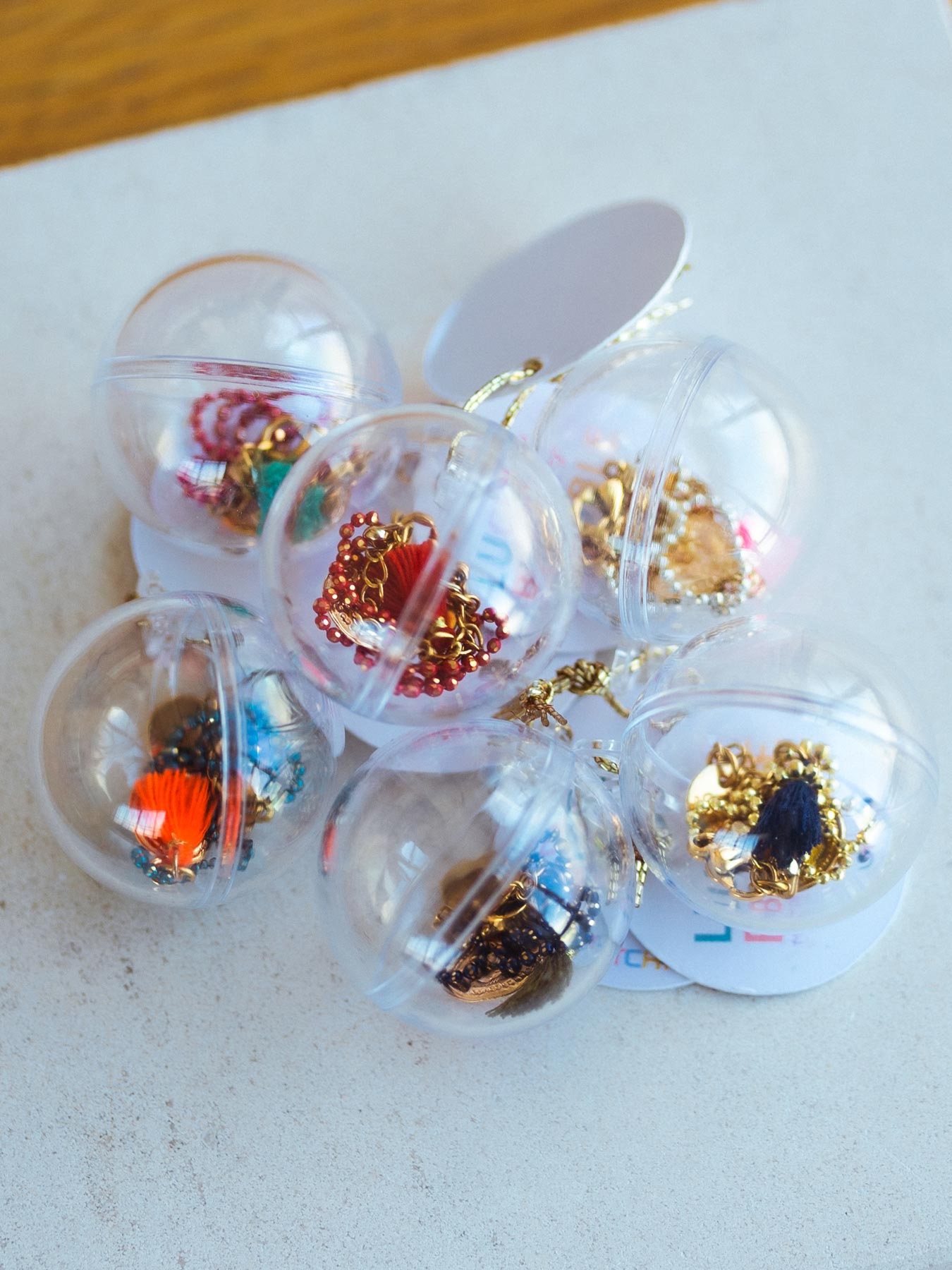A collection of clear plastic ornaments filled with colorful craft materials.