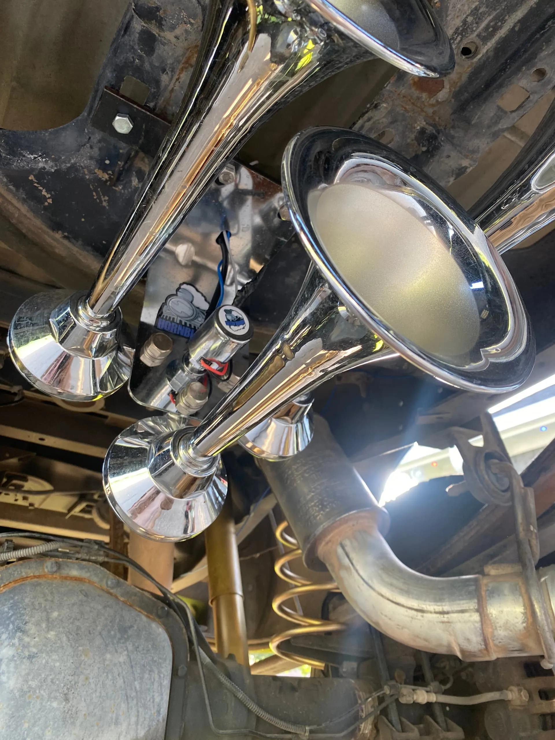 Three chrome HornBlasters train horns with solenoid valve mounted on the undercarriage of Malachi's Ford F250