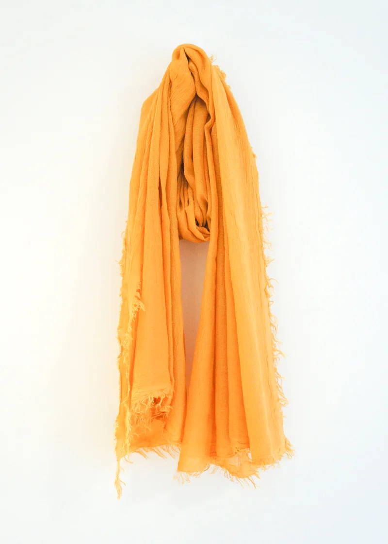 A orange bamboo scarf with raw hem detailing around the edge