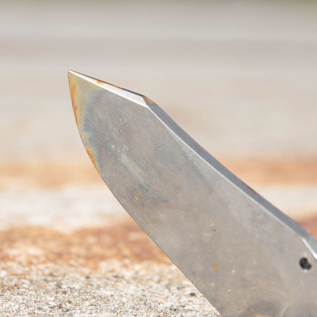 Close-up of a knife blade on a textured surface.