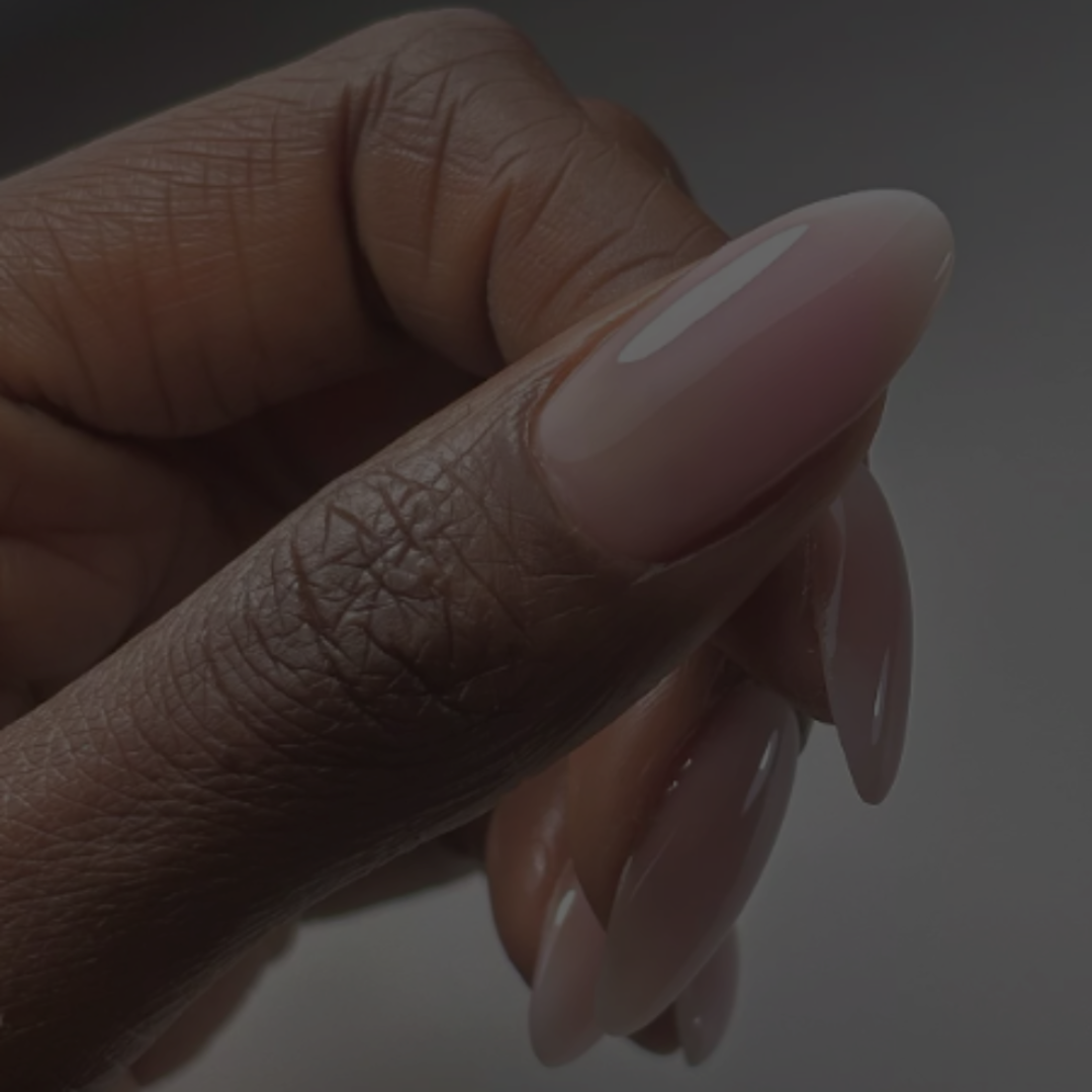 A close-up of a hand with elegantly manicured, long, nude nails.
