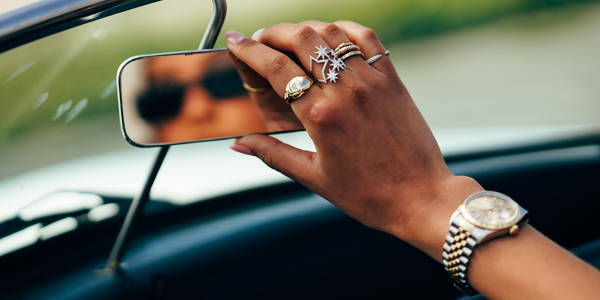 Model adjusting car mirror wearing Ring Concierge fine jewelry