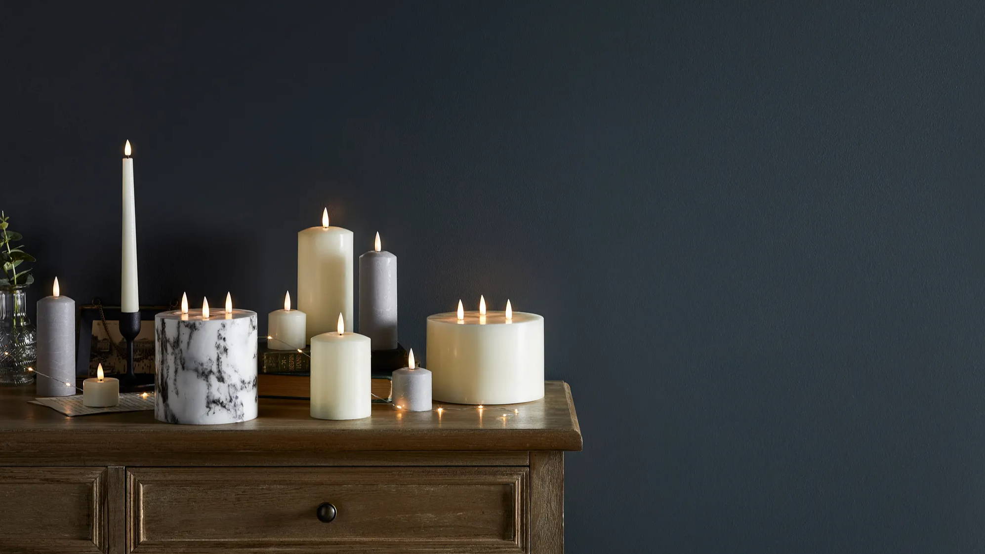 Assortment of TruGlow candles styled on table top with micro lights weaved in between the display