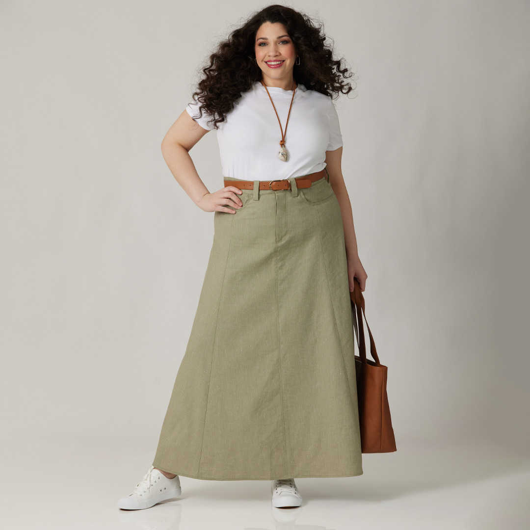 Person wearing a white top and green skirt, holding a brown bag.