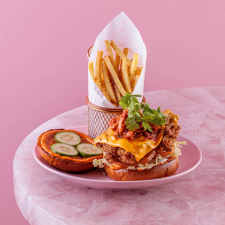 Buttermilk chicken burger with kimchi and skinny fries on pink plate