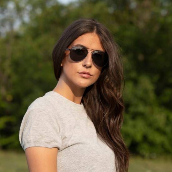 Woman styling Leo black aviator sunglasses with long hair and a beige tshirt