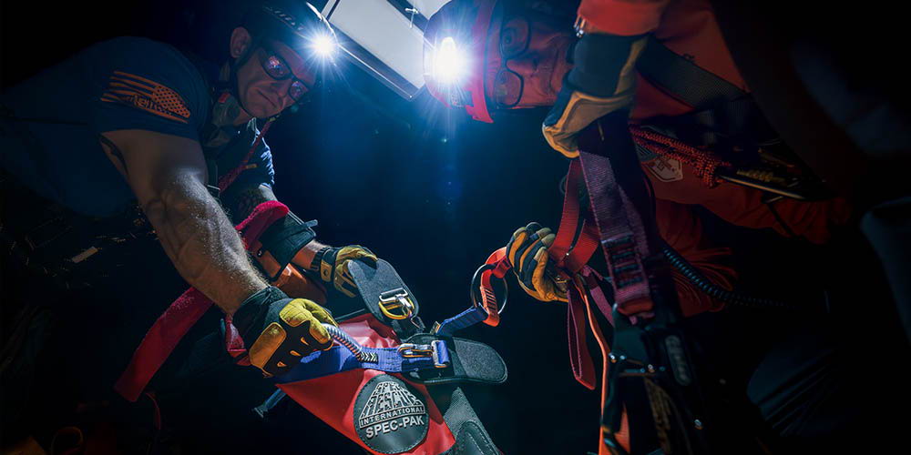 Two rescuers using the Spec Pak in a dark environment with headlamps.