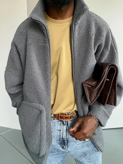 A person wearing a gray fleece jacket and holding a brown bag.
