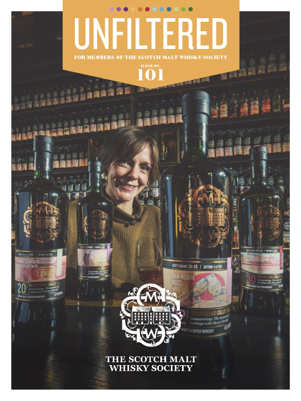 A woman smiling in front of whisky bottles on a magazine cover.