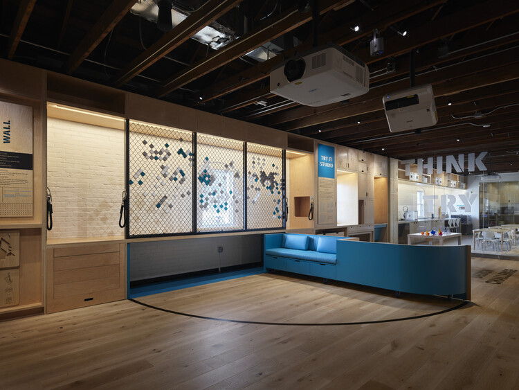 Modern interior with blue seating and large windows displaying artwork.