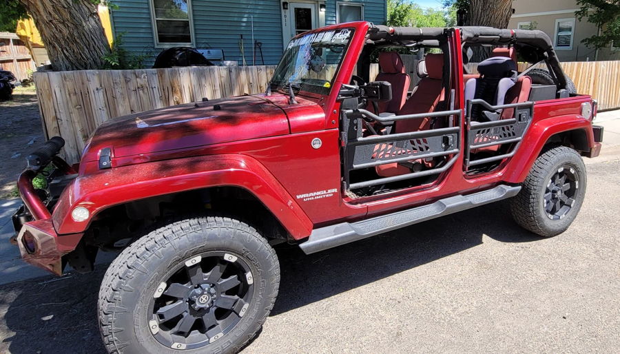 Side profile Alvin's 2013 Jeep Rubicon in metallic red with safari doors and aftermarket front bumper Outlaw Train Horn Kit HornBlasters featured install gallery photo 1