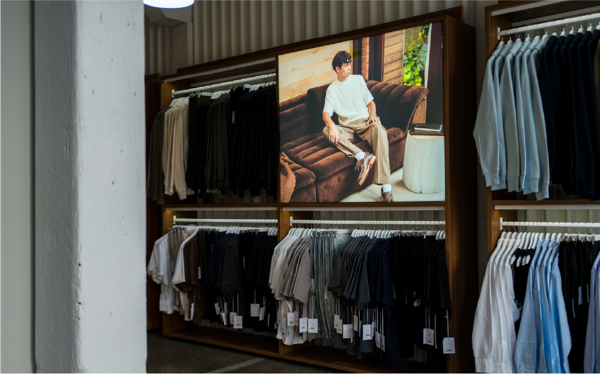 Display of clothing racks with a model on a screen.