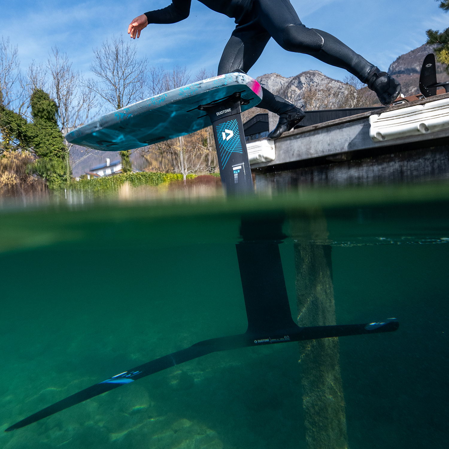 Vue sous l'eau d'une planche de pumping près d'un quai, dans une eau limpide.