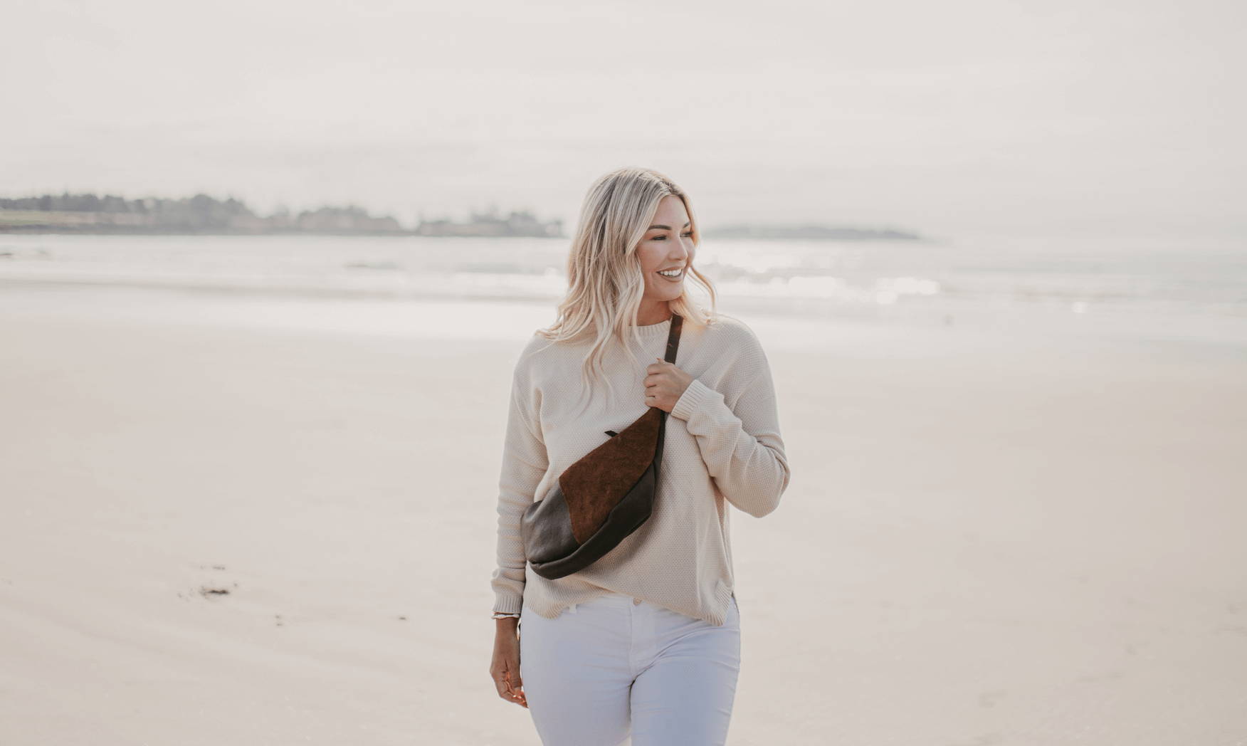 Brown leather crossbody bag with seaweed tassel on the beach