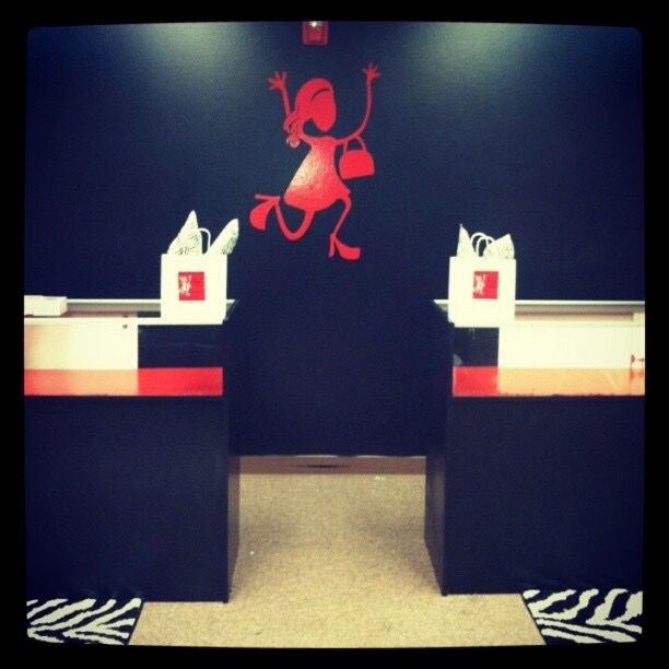 Photo by She's Happy Hair of the checkout counters at the brand's original location. The photo features a red mascot of a dancing lady on the back wall, branded gift bags, and zebra print rugs.