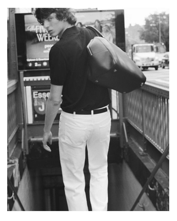 A person in a black shirt and white pants descending stairs.