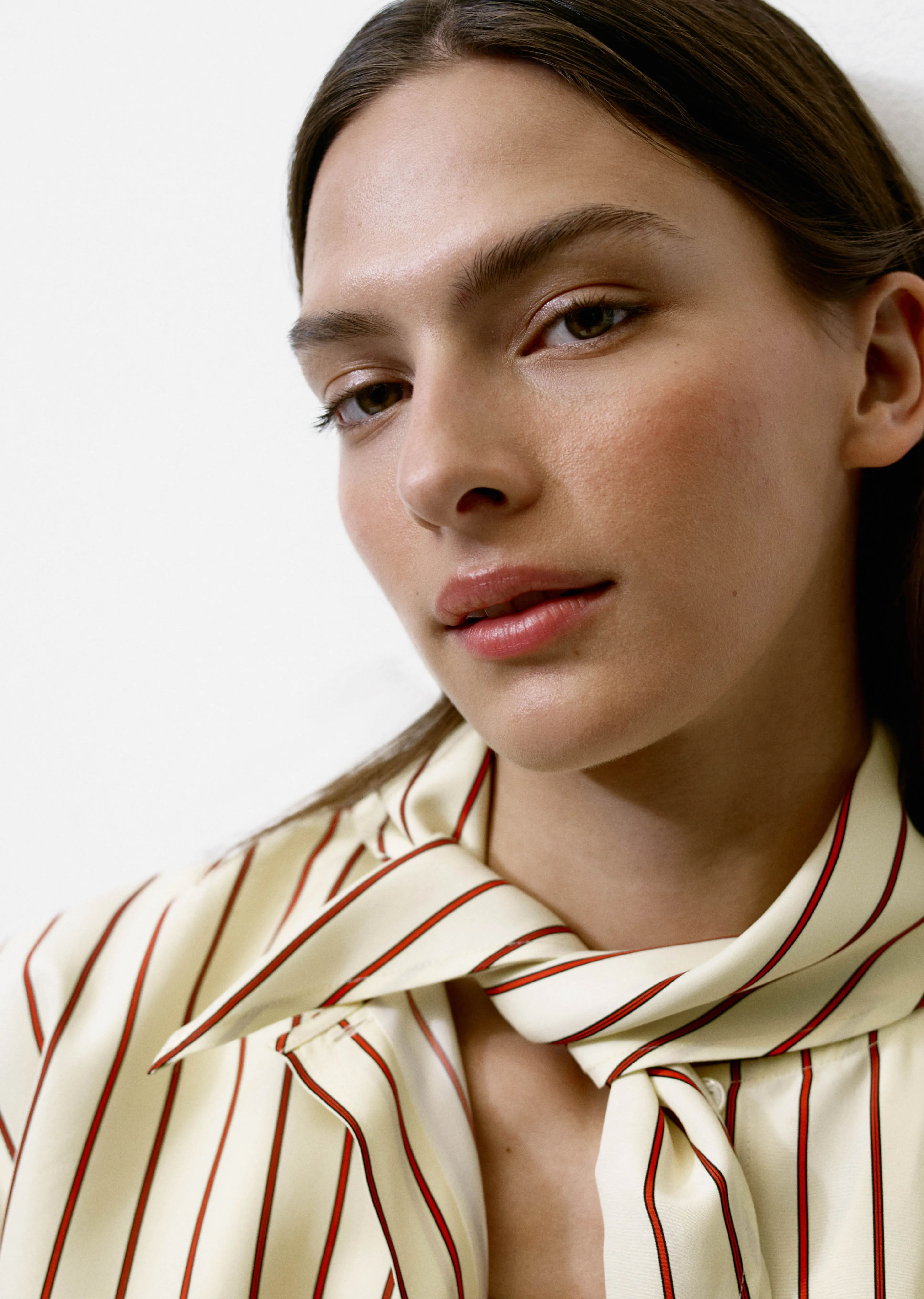 Portrait of a woman with a striped shirt and scarf against a neutral background.