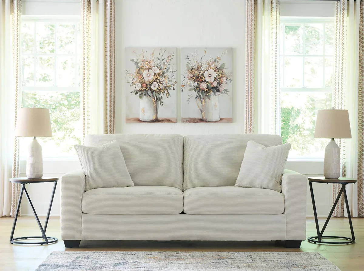 A cozy living room with a white sofa and floral artwork.