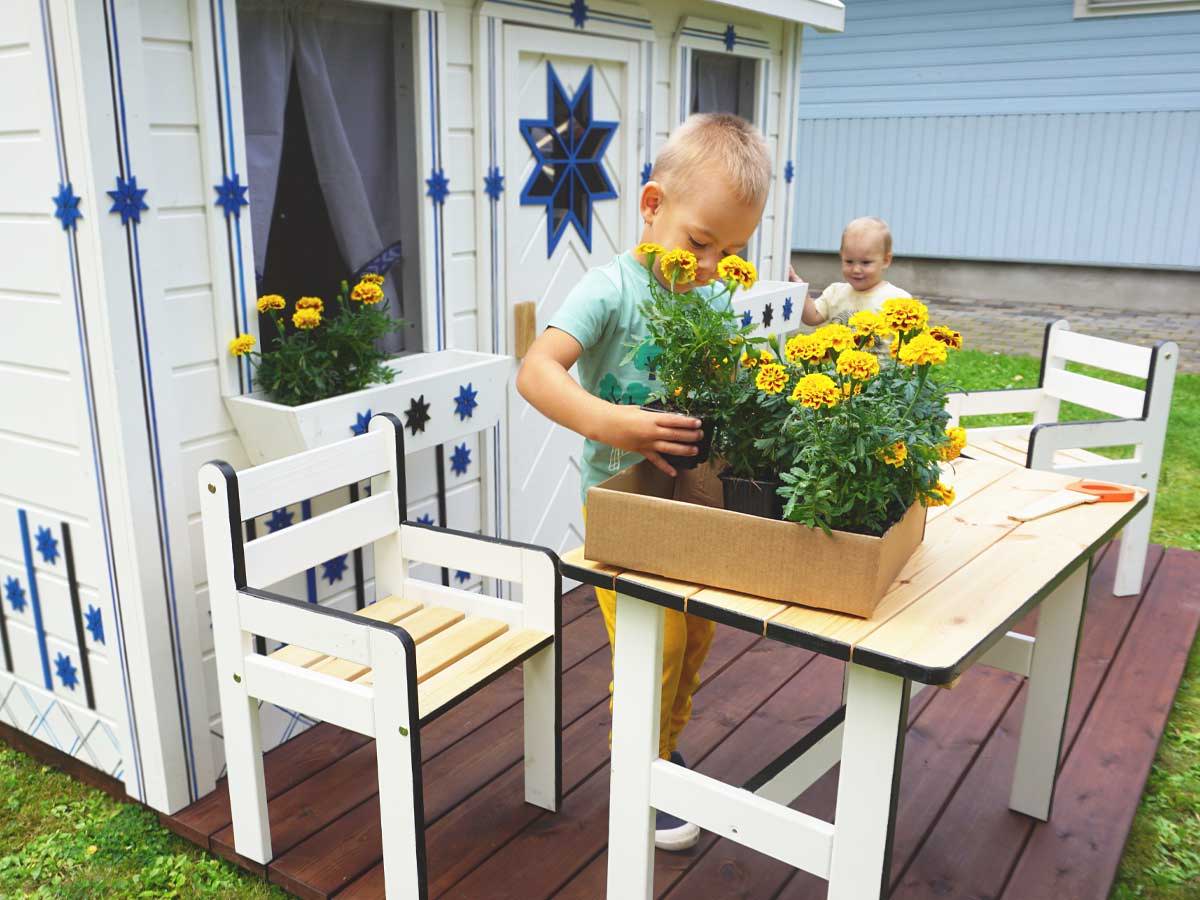 Boy plants flowers onKids Outdoor Playhouse terrace by WholeWoodPlayhouses