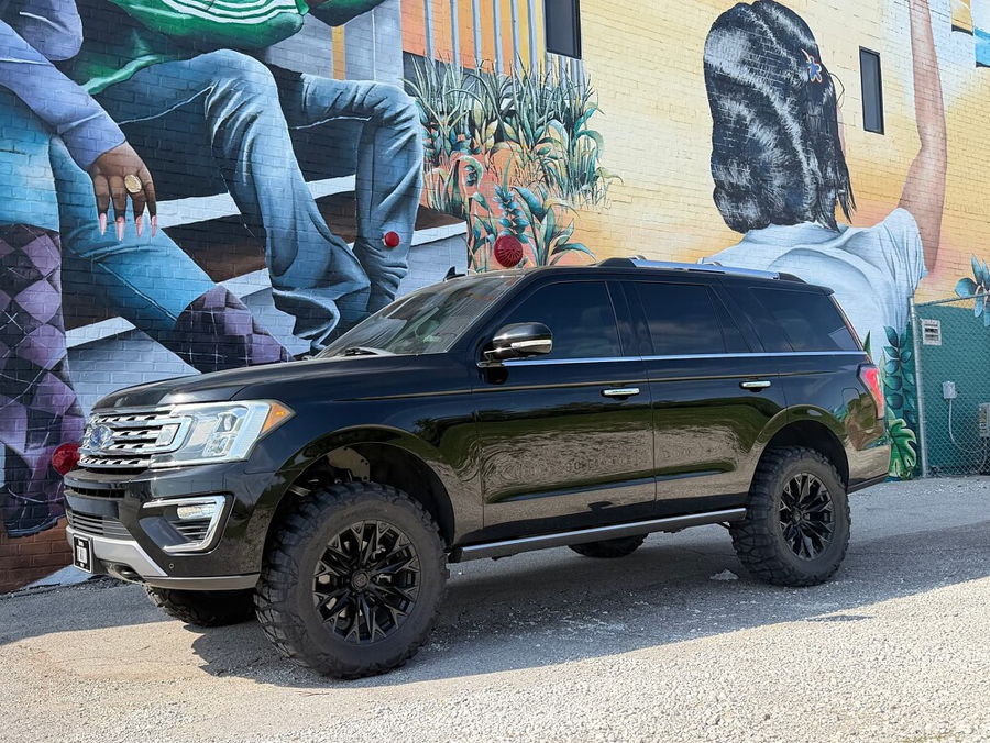 Front-three-quarter view Troy's black lifted 2018 Ford Expedition parked before colorful brick mural wall gallery photo 8