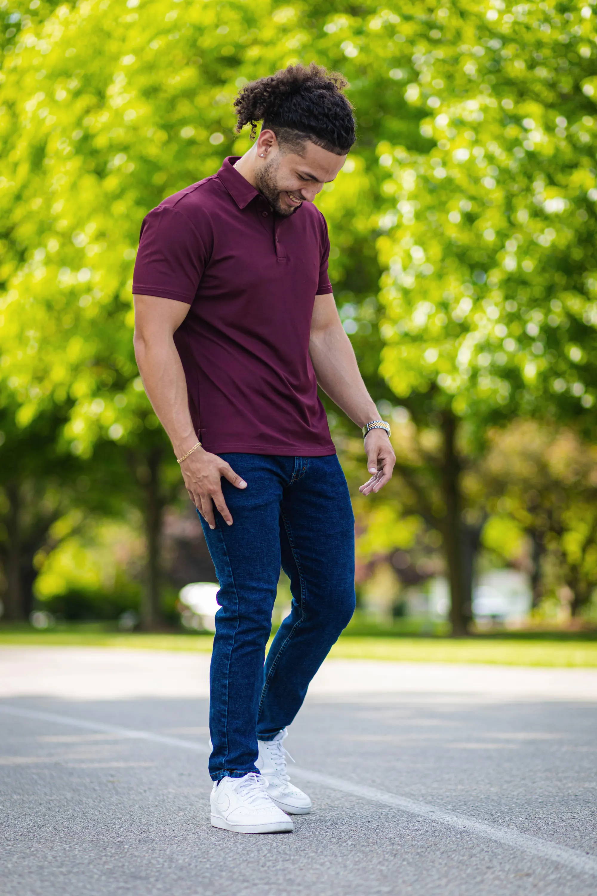 Man looking down smiling wearing burgundy t shirt and dark wash stretch jeans from under510.com