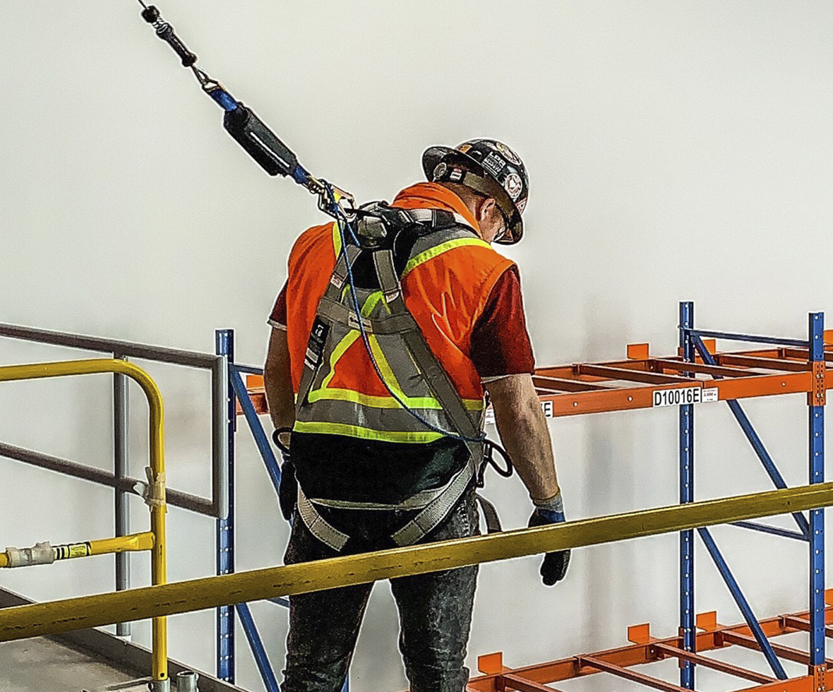 Consruction worker at height looking down, wearing a FlowTech LTE harness attached to a self-retracting lifeline