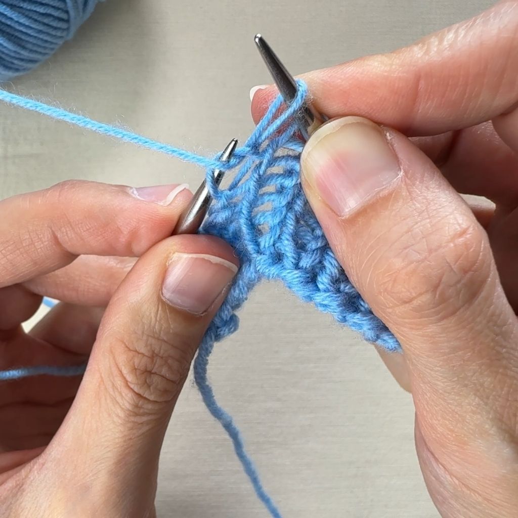 Linksverschränkt stricken: Die neu gebildete Masche wird nun auf die rechte Nadel gehoben.