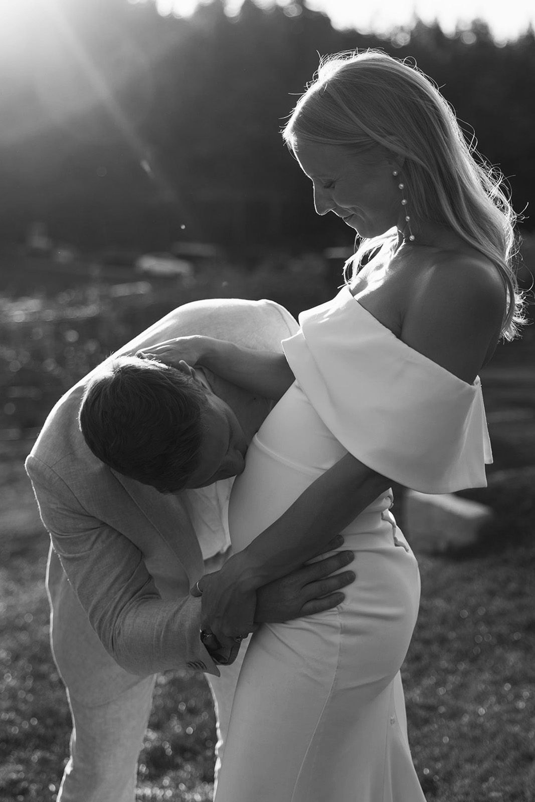 Couple in a romantic pose, expecting a child, captured in black and white.