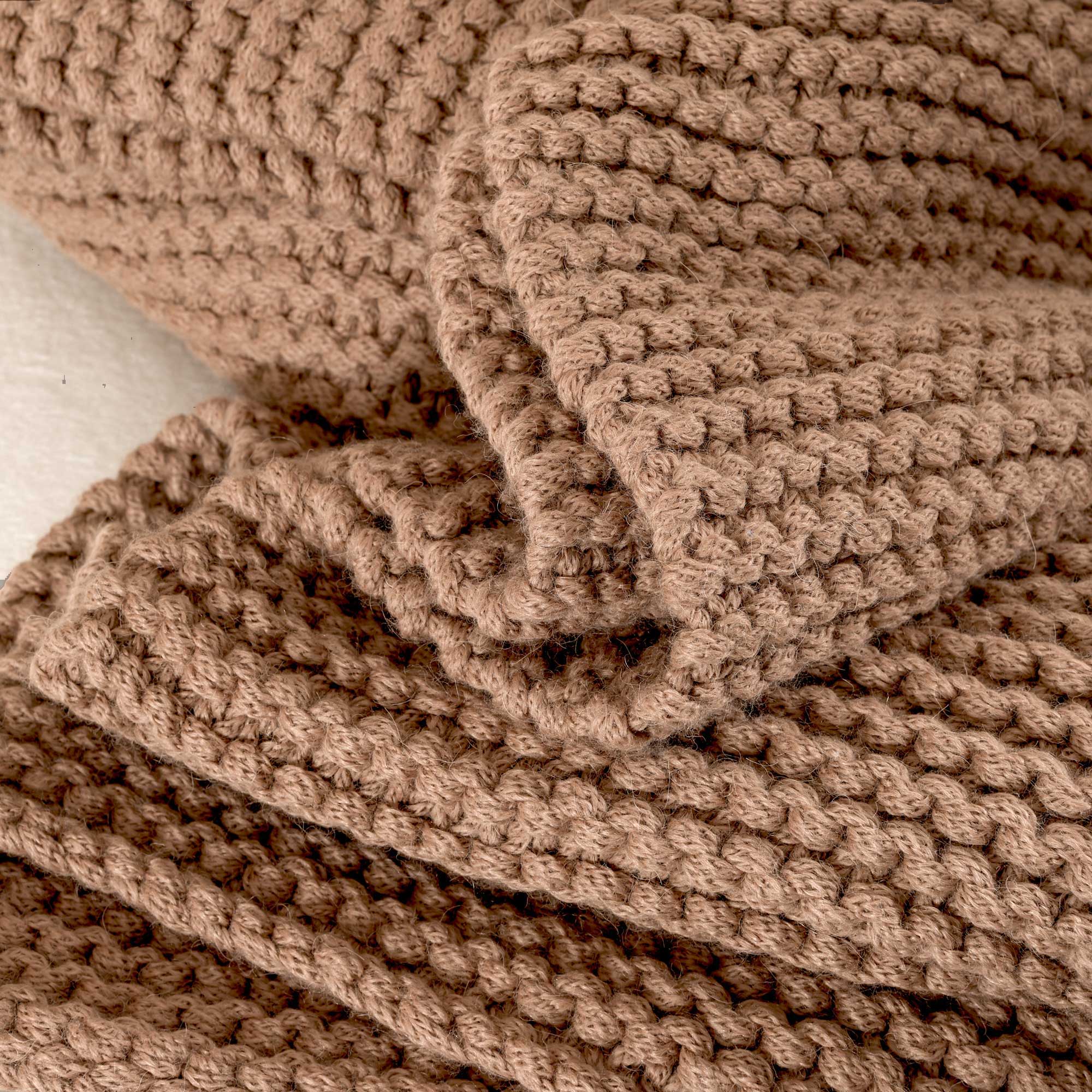 Textured brown knitted blanket draped over a surface.