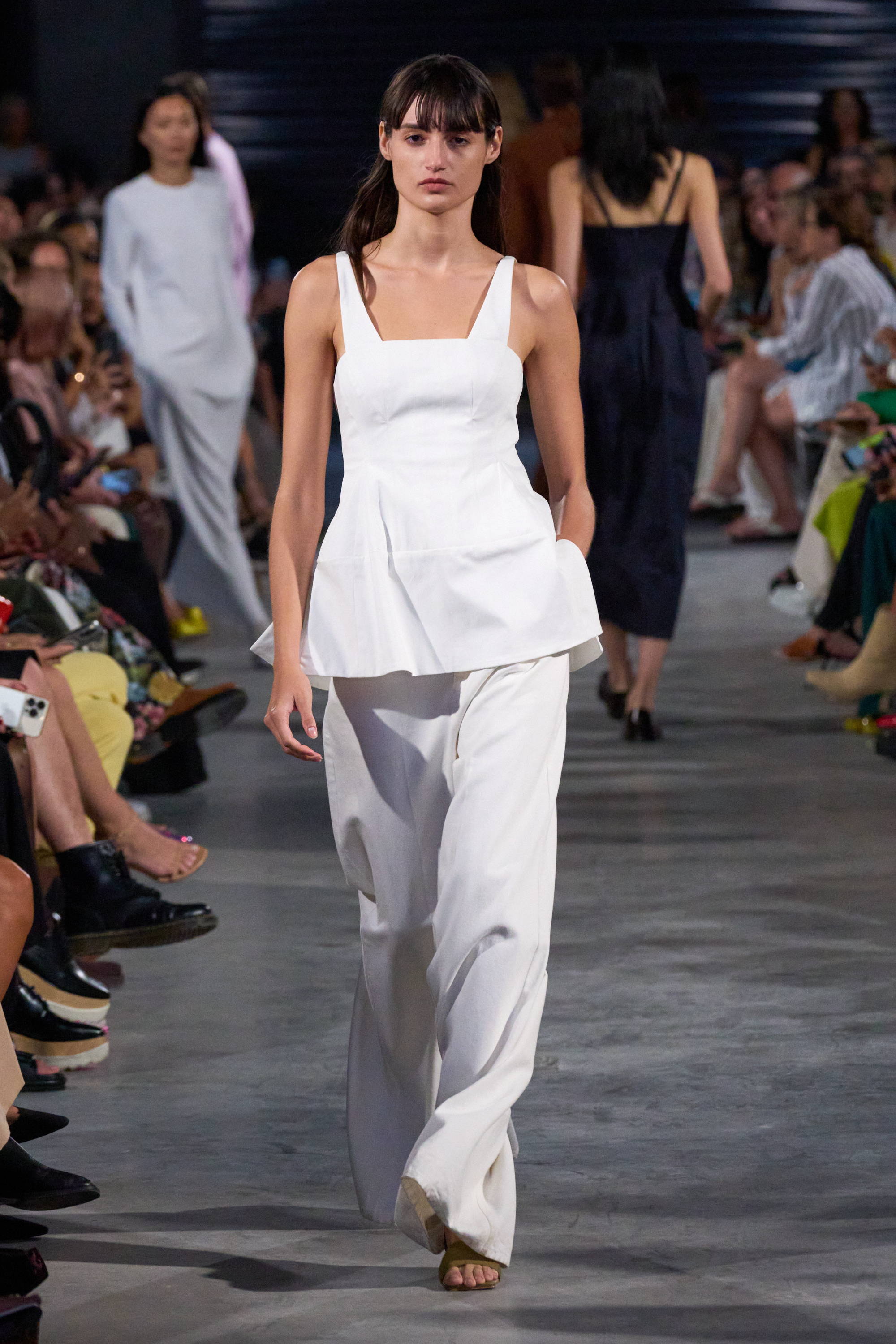 Model on a runway wearing tank top and pants
