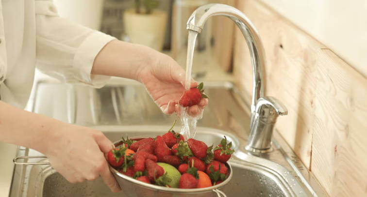 woman washing strawberries at sink