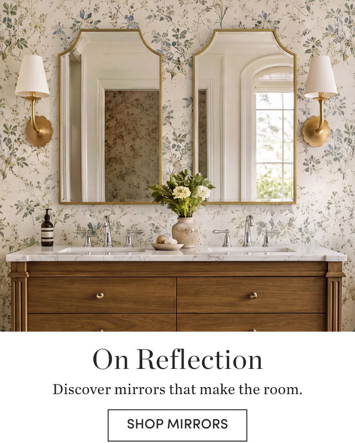 Decorative mirrors above a wooden dresser in a floral wallpapered room.