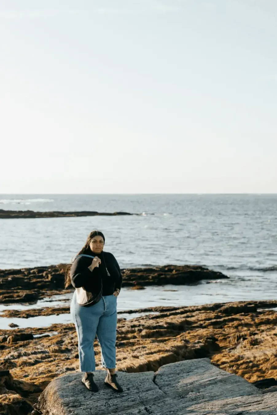 woman wearing black leather bag on the rocky coast