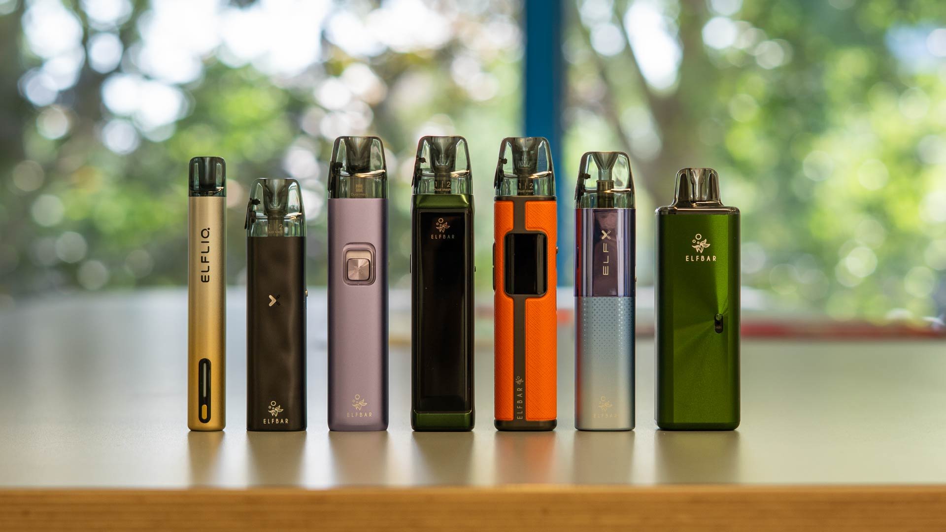 Various vaping devices arranged on a table with a blurred background.