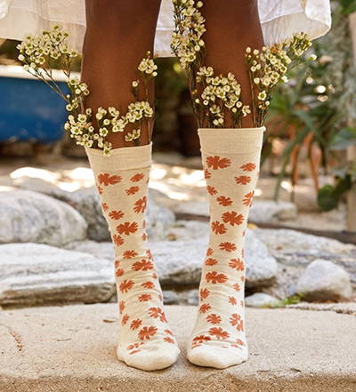 Conscious Step Socks with orange flowers on a white sock supporting the mission to prevent violence against women