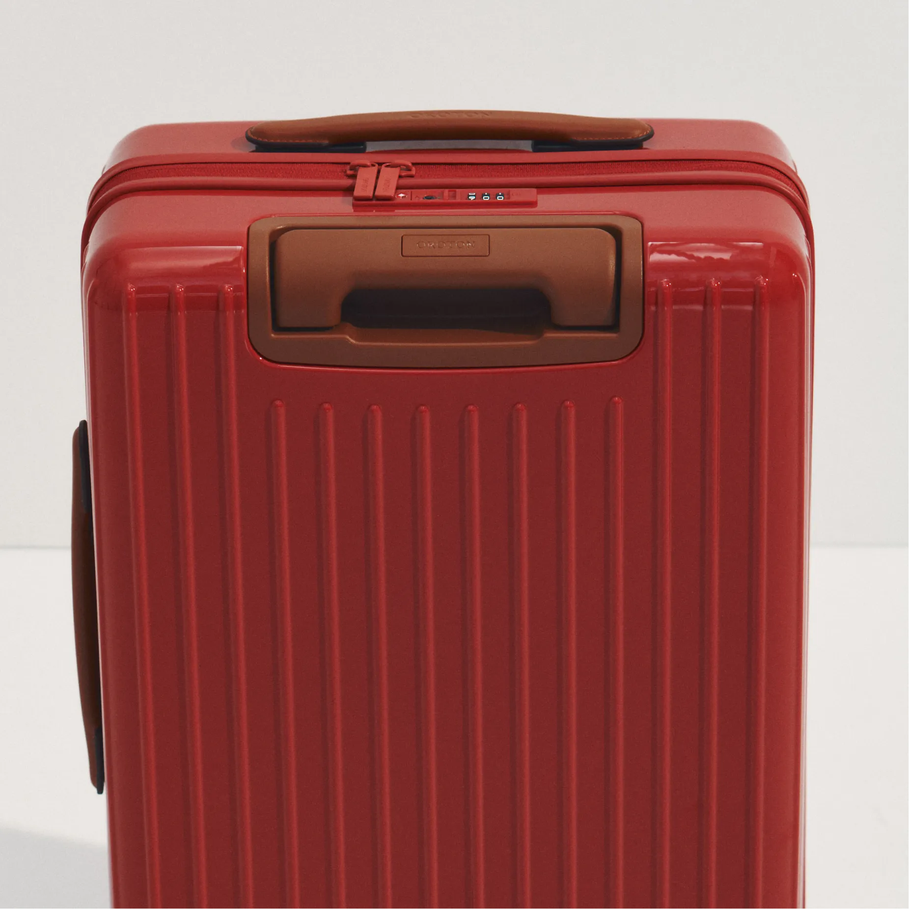 Red suitcase with vertical grooves and a brown handle.
