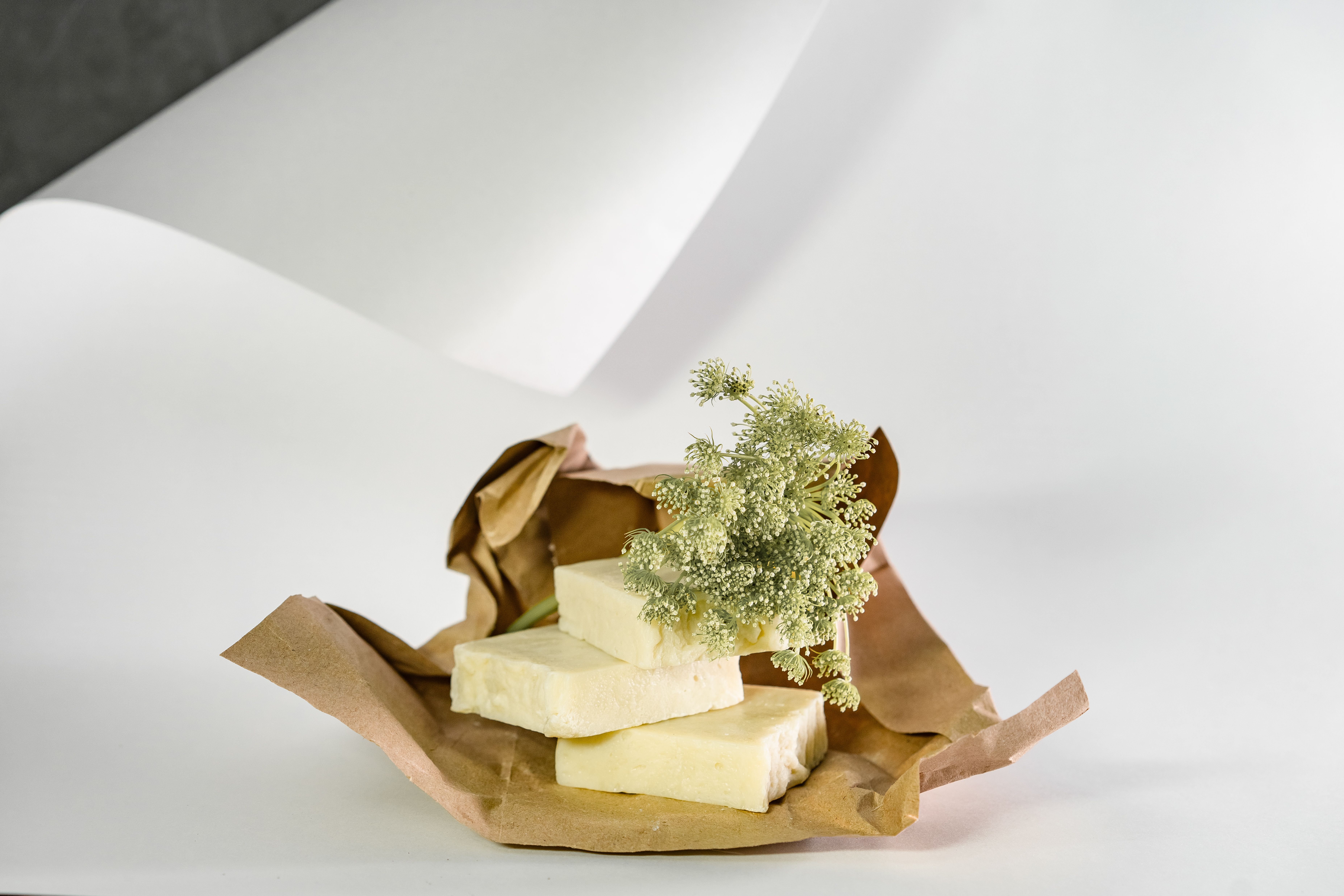 Beef tallow wrapped in paper with a small pile of herbs.