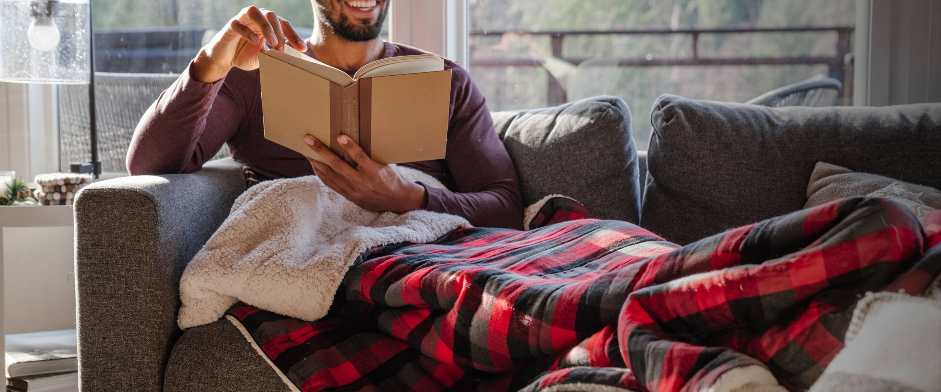 Man reading a book under his wool flannel blanket