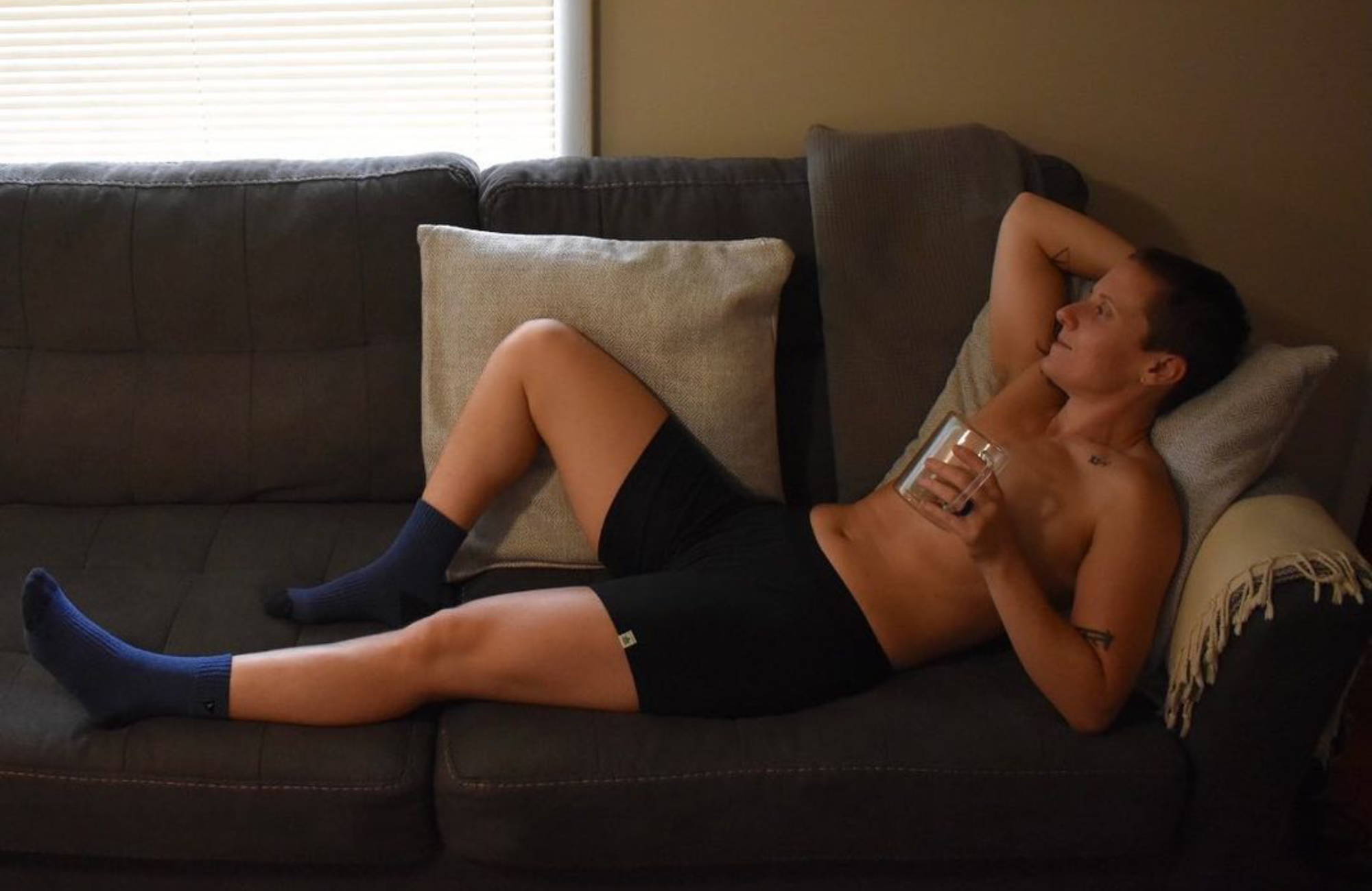 man on lounging on a sofa with one arm behind their head in black boxer briefs 