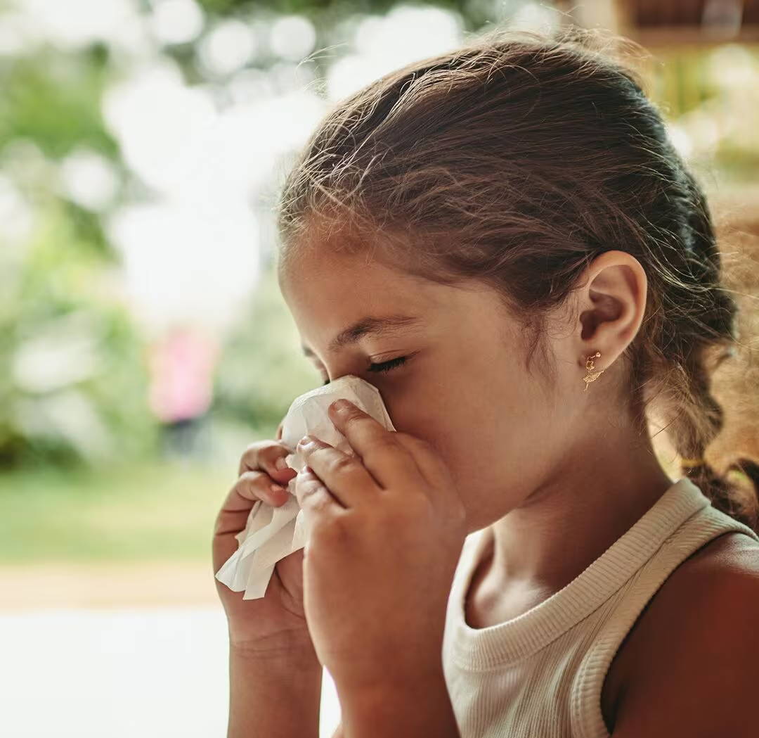 Holčička kýchá do papírového kapesníku a smrká – možná by jí lék na alergii mohl poskytnout úlevu od nepříjemné alergické rýmy