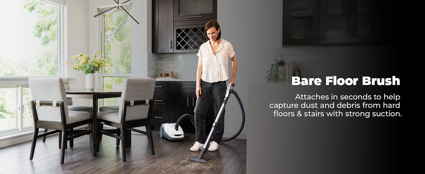 Person using a vacuum with a bare floor brush in a modern kitchen.