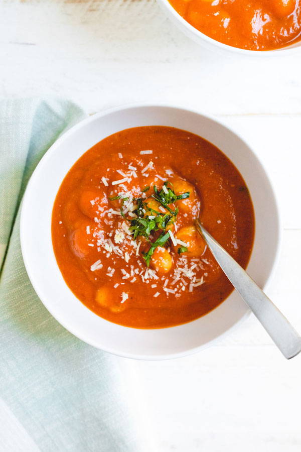 bowl of creamy tomato soup with gnocchi sprinkled with cheese