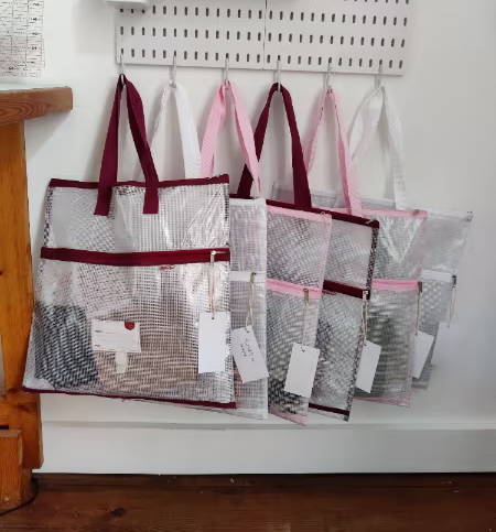 six project bags hanging on a peg board in a sewing room