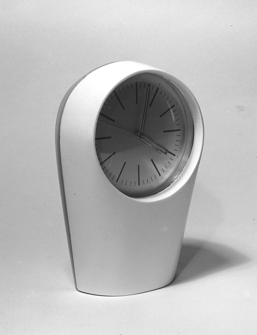 A modern white clock with a curved design.